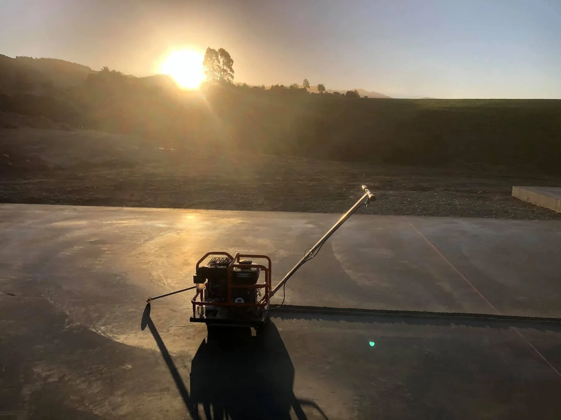 Finished concrete slab with saw cuts at dusk on a South Canterbury site, hills behind