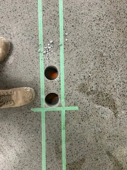 Core holes marked in green tape on a South Canterbury supermarket floor with the drilled openings between them