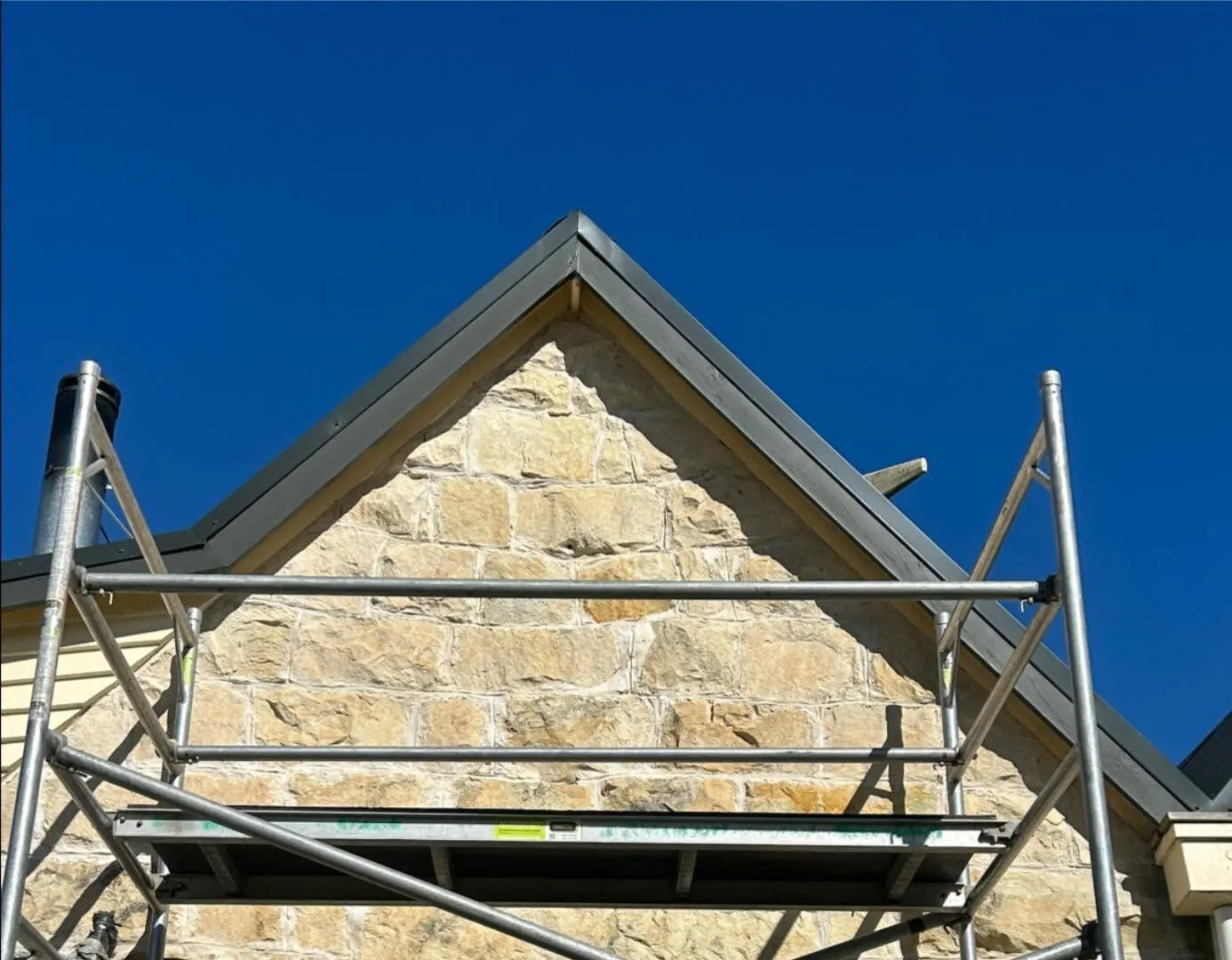 Scaffold against a heritage stone gable end in South Canterbury where an attic window and lintel slot have been cut