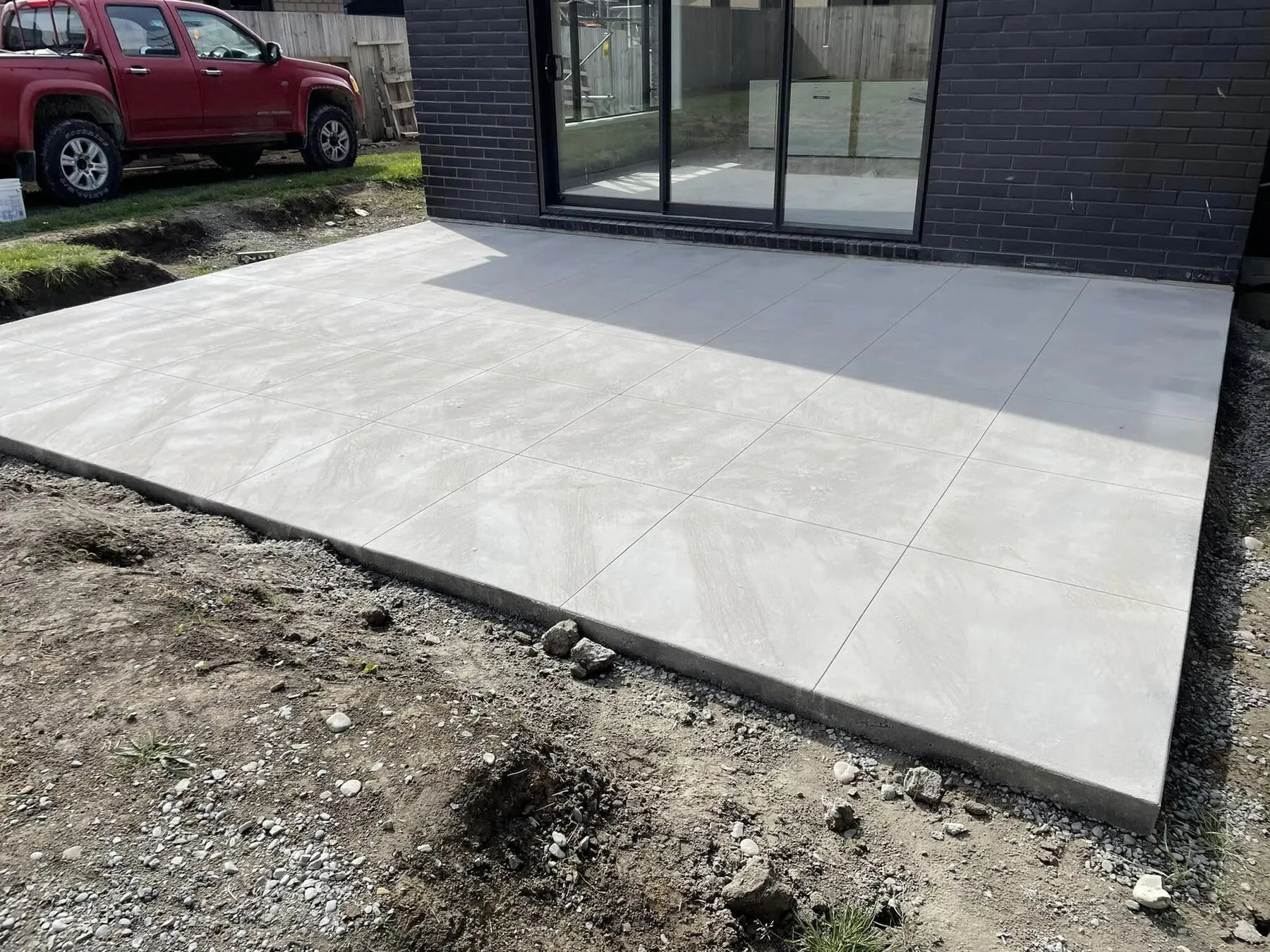 Finished patio outside a dark brick house cut into a grid of large squares
